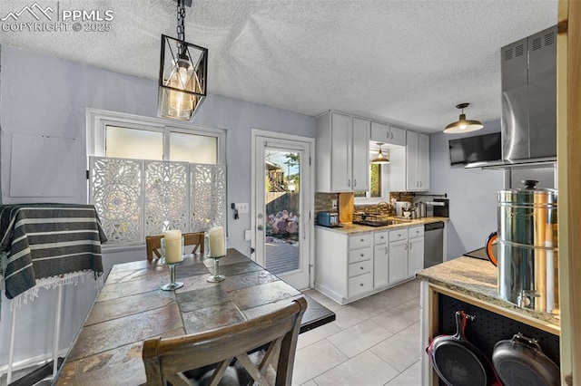 1065 N 19th St, Colorado Springs, CO 80904 - kitchen with decorative backsplash, dishwasher, white cabinets, light tile patterned floors, and hanging light fixtures