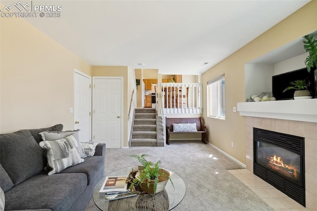 carpeted living area with baseboards, a fireplace, and stairway