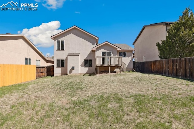 rear view of property with a lawn, a fenced backyard, stucco siding, and a deck
