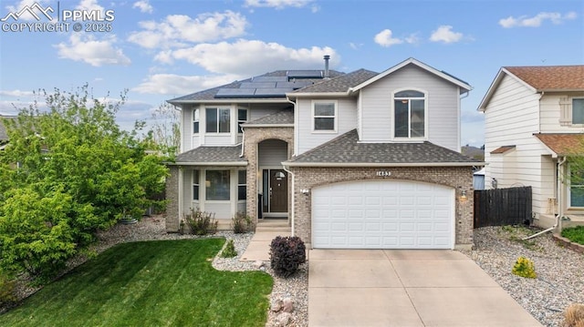 traditional-style home featuring fence, roof with shingles, brick siding, roof mounted solar panels, and concrete driveway