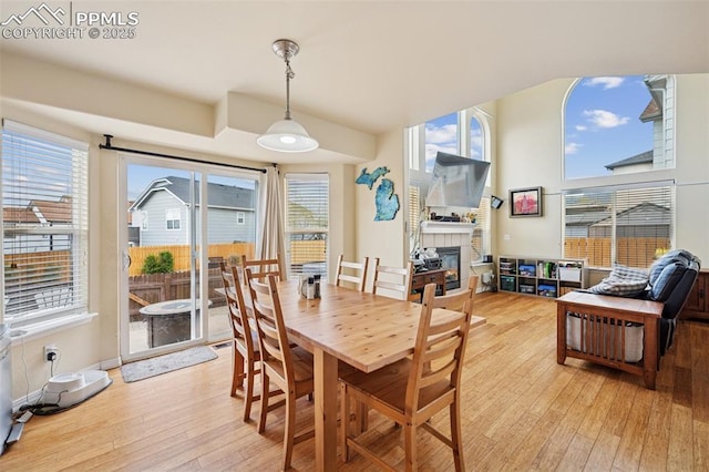 dining space with light wood-style flooring and a glass covered fireplace