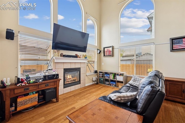 living area featuring a high ceiling, a fireplace, and wood finished floors