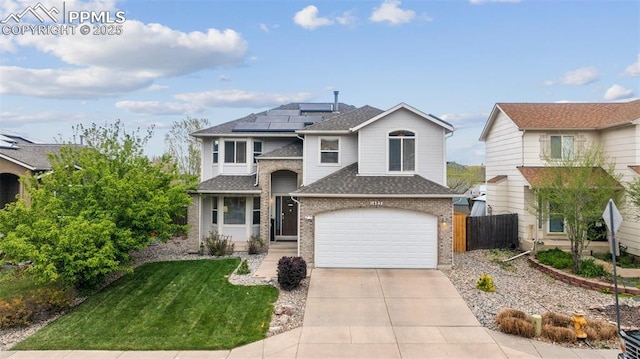 traditional-style house with brick siding, fence, roof mounted solar panels, concrete driveway, and an attached garage