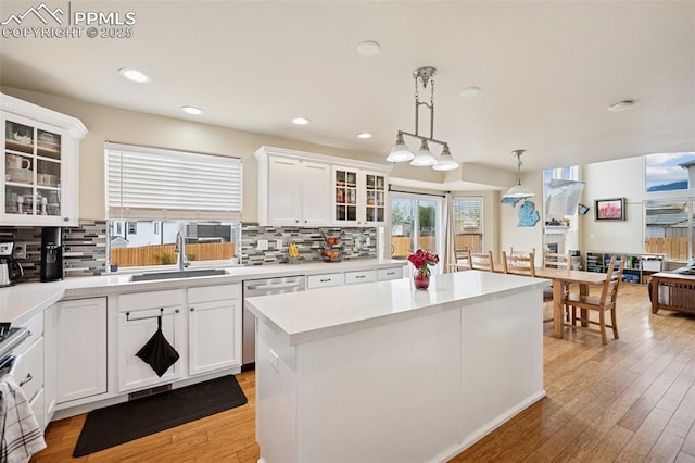 kitchen featuring light countertops, decorative backsplash, a sink, and dishwasher