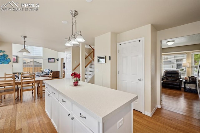 kitchen featuring white cabinets, light countertops, light wood-style flooring, and a center island
