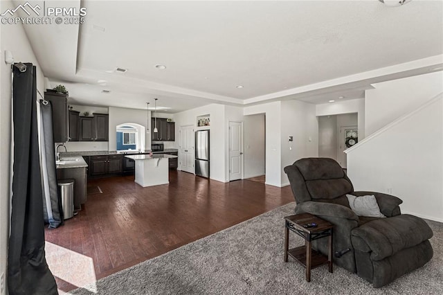 living room with recessed lighting, baseboards, a tray ceiling, and dark wood finished floors