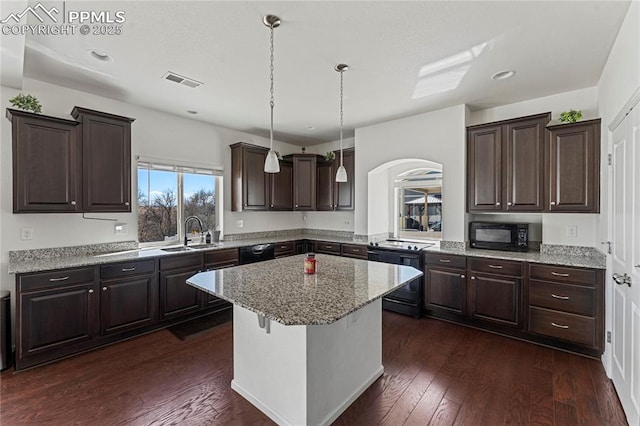 kitchen featuring visible vents, arched walkways, dark brown cabinets, a sink, and black appliances