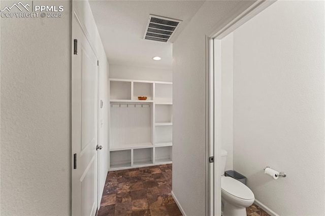bathroom with visible vents, baseboards, stone finish floor, and toilet