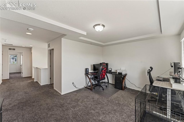 carpeted home office with baseboards, a tray ceiling, and visible vents