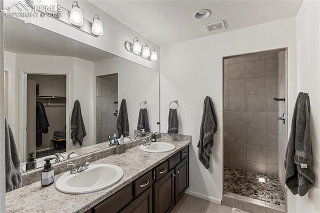 full bath with a walk in shower, visible vents, a sink, and a spacious closet