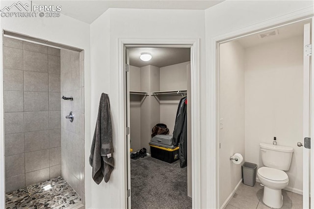 full bathroom featuring visible vents, a walk in closet, toilet, and tiled shower