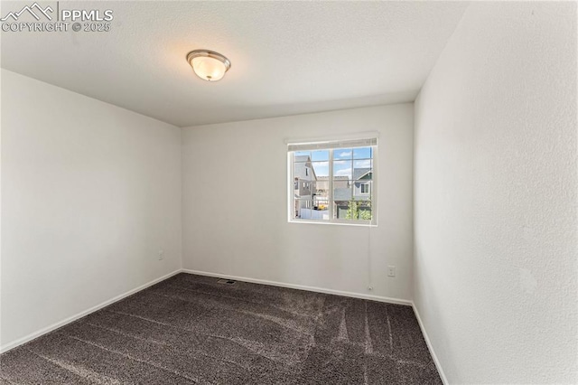 empty room featuring baseboards and dark colored carpet