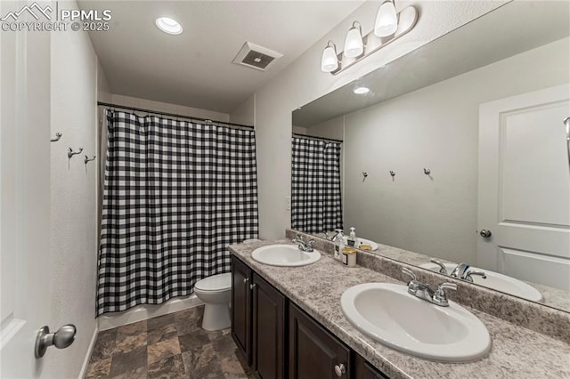bathroom with visible vents, a sink, stone finish floor, and toilet