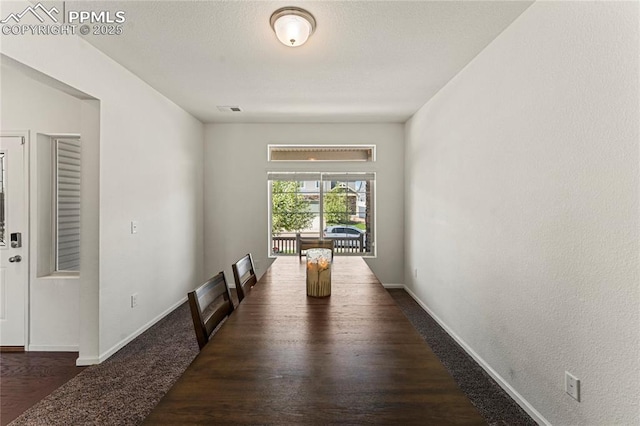 unfurnished dining area featuring baseboards, carpet floors, wood finished floors, and visible vents