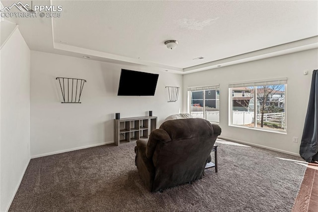carpeted living area featuring baseboards, a tray ceiling, and visible vents
