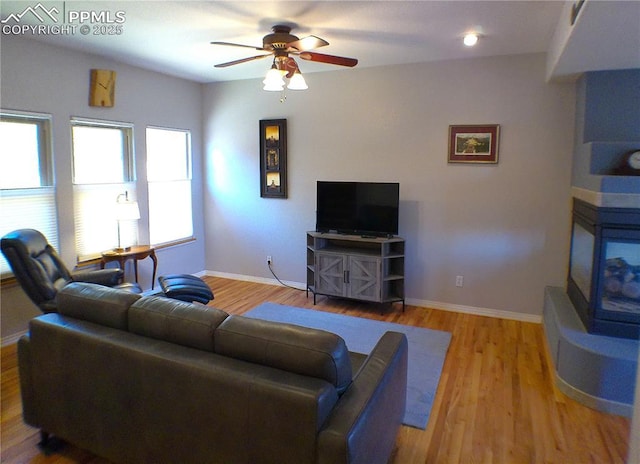living area featuring baseboards, ceiling fan, and wood finished floors