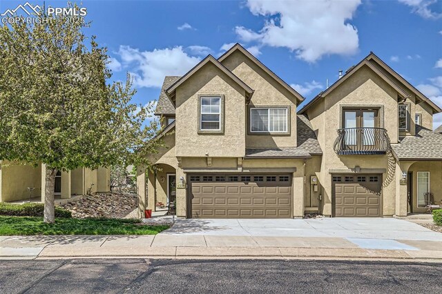 4338 Alder Springs Vw, Colorado Springs, CO 80922 - view of front of property with stucco siding, a garage, a balcony, driveway, and roof with shingles