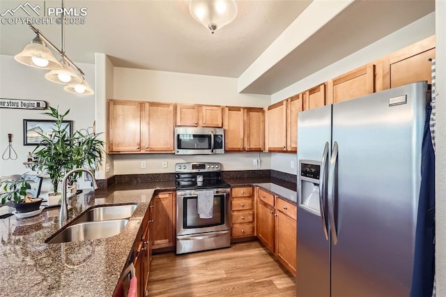 4338 Alder Springs Vw, Colorado Springs, CO 80922 - kitchen with stainless steel appliances, a sink, dark stone countertops, light wood-style floors, and hanging light fixtures