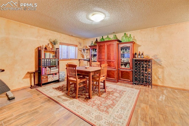 620 Coveglen Ct, Colorado Springs, CO 80906 - dining area featuring baseboards, light wood-style flooring, a textured ceiling, and a textured wall