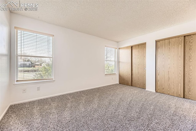 1351 Cathay Ct Unit 102, Arapahoe, CO 80017 - unfurnished bedroom featuring a textured ceiling, multiple closets, and carpet