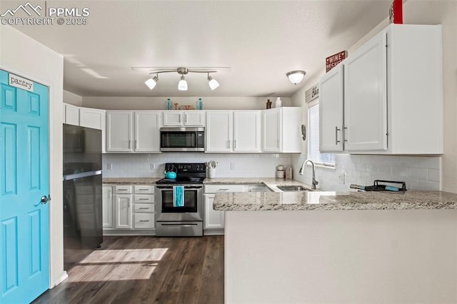 kitchen featuring appliances with stainless steel finishes, a sink, a peninsula, and white cabinets
