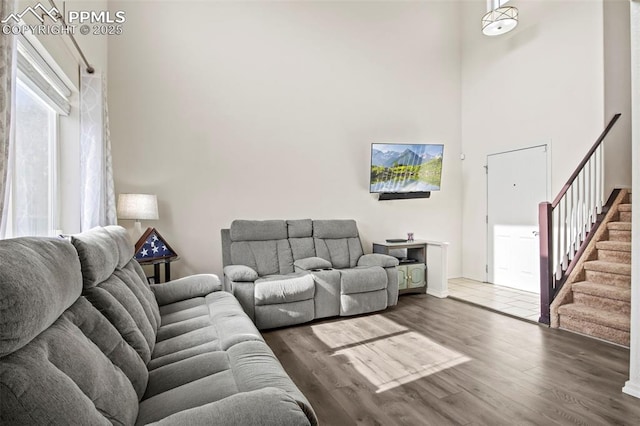 living room with stairs, a towering ceiling, and wood finished floors