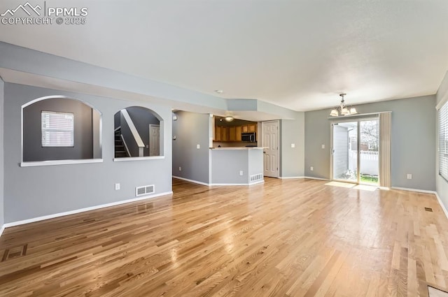 7824 Bengali Ln, Colorado Springs, CO 80923 - unfurnished living room with a notable chandelier, visible vents, baseboards, and light wood-type flooring