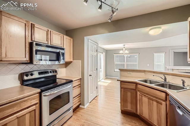 7824 Bengali Ln, Colorado Springs, CO 80923 - kitchen with an inviting chandelier, a sink, light wood-style floors, stainless steel appliances, and tasteful backsplash
