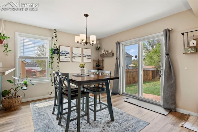 dining space with a chandelier, light wood-style flooring, and baseboards