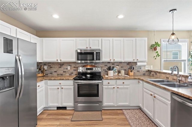 kitchen featuring stainless steel appliances, a sink, white cabinetry, light wood finished floors, and recessed lighting