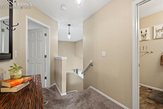 corridor with an upstairs landing, baseboards, and carpet floors