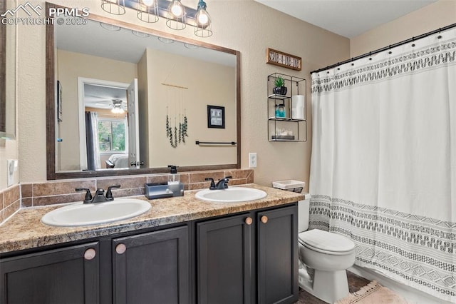 full bath featuring tasteful backsplash, double vanity, toilet, a textured wall, and a ceiling fan