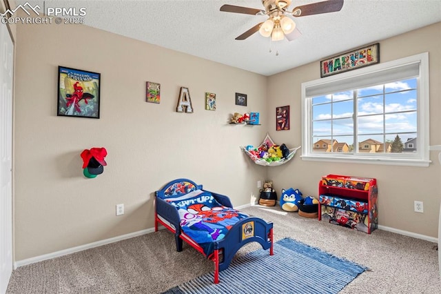carpeted bedroom with a textured ceiling, baseboards, and a ceiling fan