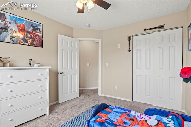 bedroom with light colored carpet, a closet, ceiling fan, baseboards, and a textured ceiling