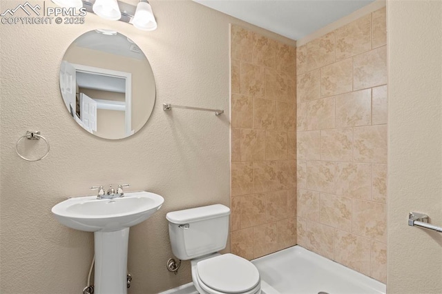 full bath featuring toilet, a stall shower, and a sink