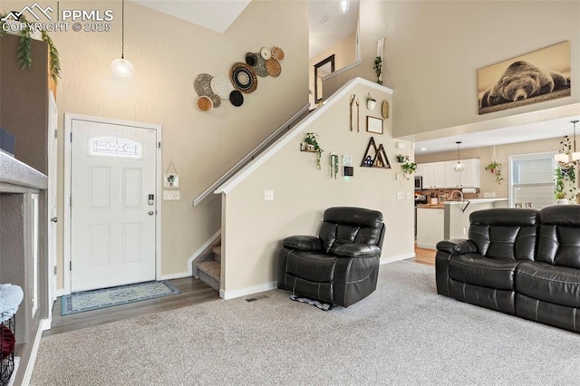 living area with a high ceiling, stairs, baseboards, and carpet floors