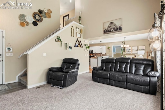 living room with stairway, carpet, a towering ceiling, and baseboards