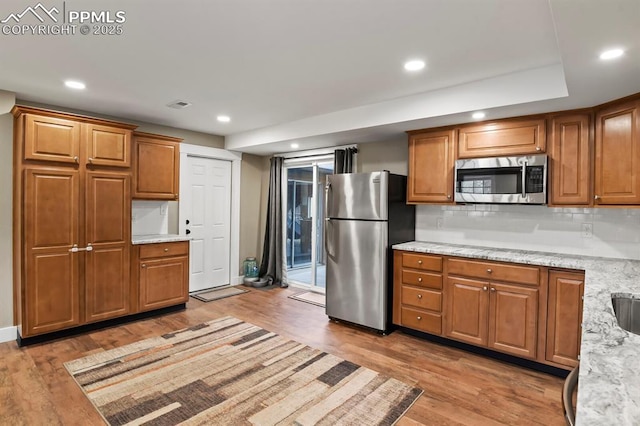 15 Newport Cir, Colorado Springs, CO 80906 - kitchen with stainless steel appliances, recessed lighting, brown cabinetry, and light wood-style floors