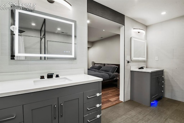15 Newport Cir, Colorado Springs, CO 80906 - full bath featuring wood finished floors, tile walls, ensuite bathroom, two vanities, and a sink