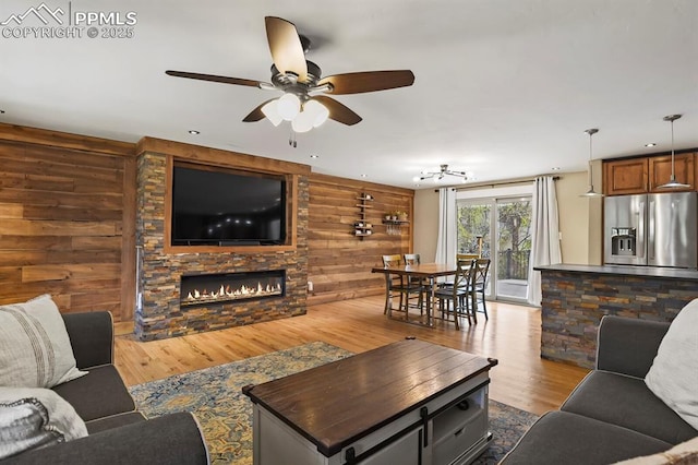 15 Newport Cir, Colorado Springs, CO 80906 - living area with wooden walls, a fireplace, a ceiling fan, and wood finished floors