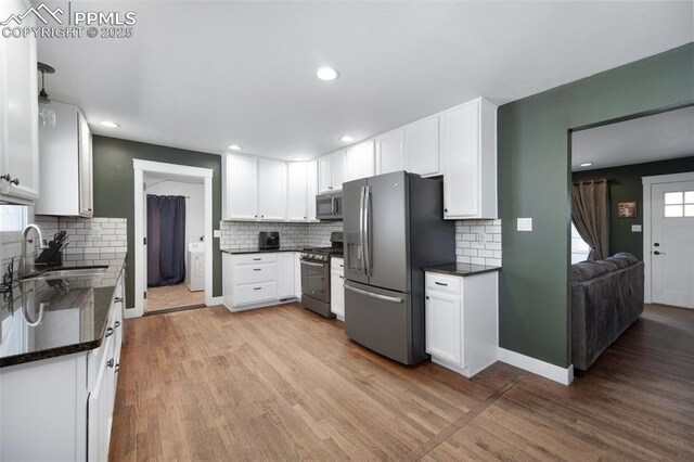 208 Davie Dr, Colorado Springs, CO 80911 - kitchen with wood finished floors, white cabinets, a sink, backsplash, and stainless steel appliances