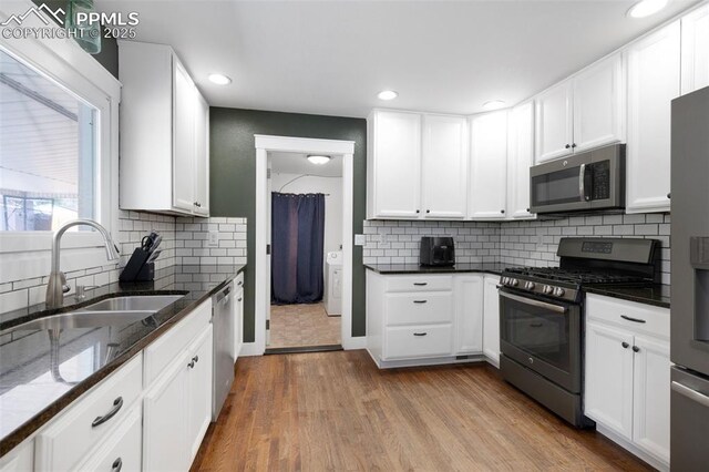 208 Davie Dr, Colorado Springs, CO 80911 - kitchen featuring a sink, white cabinets, dark stone countertops, light wood-style floors, and stainless steel appliances