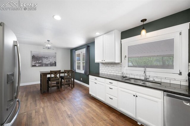 208 Davie Dr, Colorado Springs, CO 80911 - kitchen with decorative backsplash, dark wood-style flooring, dark countertops, a sink, and stainless steel appliances