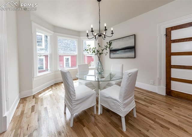 dining room with baseboards, an inviting chandelier, and light wood finished floors