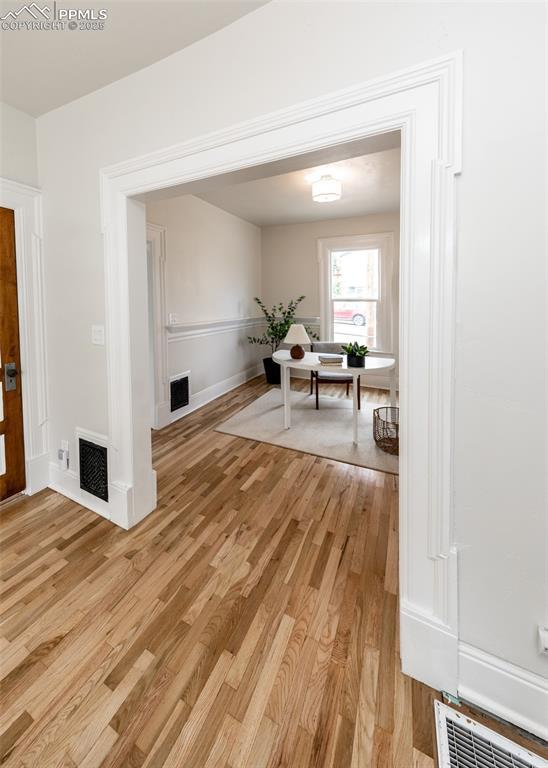 interior space with baseboards, light wood-type flooring, and visible vents