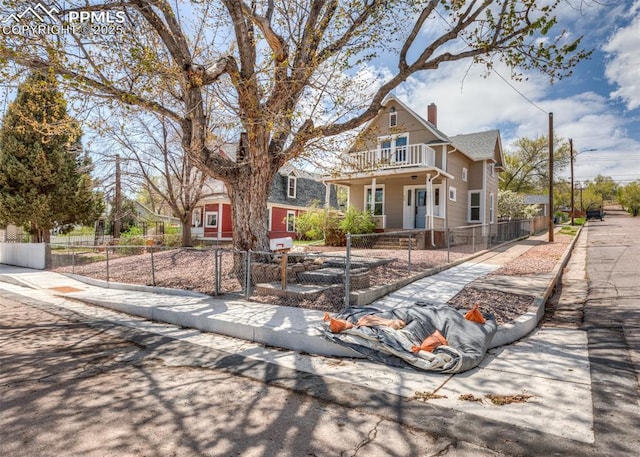 view of front of house featuring a fenced front yard, a porch, a gate, a chimney, and a balcony