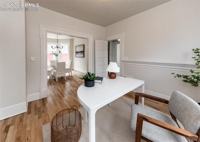 office area with baseboards, light wood finished floors, and a chandelier