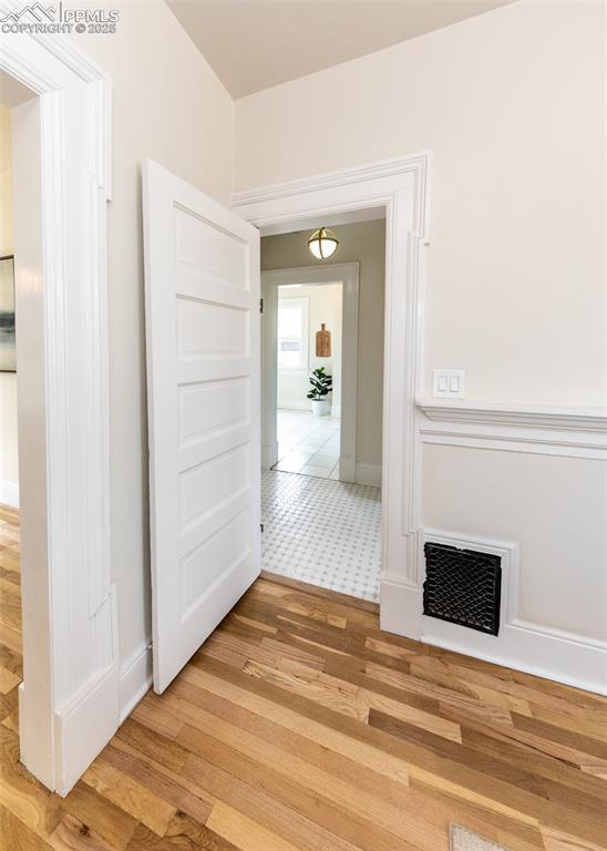 hall featuring baseboards, visible vents, and light wood-style floors