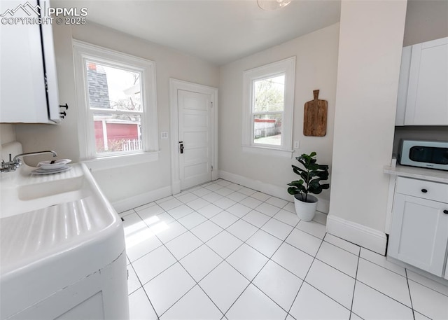 doorway to outside featuring light tile patterned floors, baseboards, and a healthy amount of sunlight
