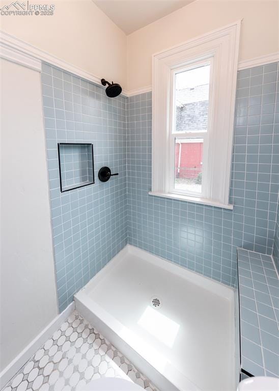 full bathroom with baseboards and a tile shower